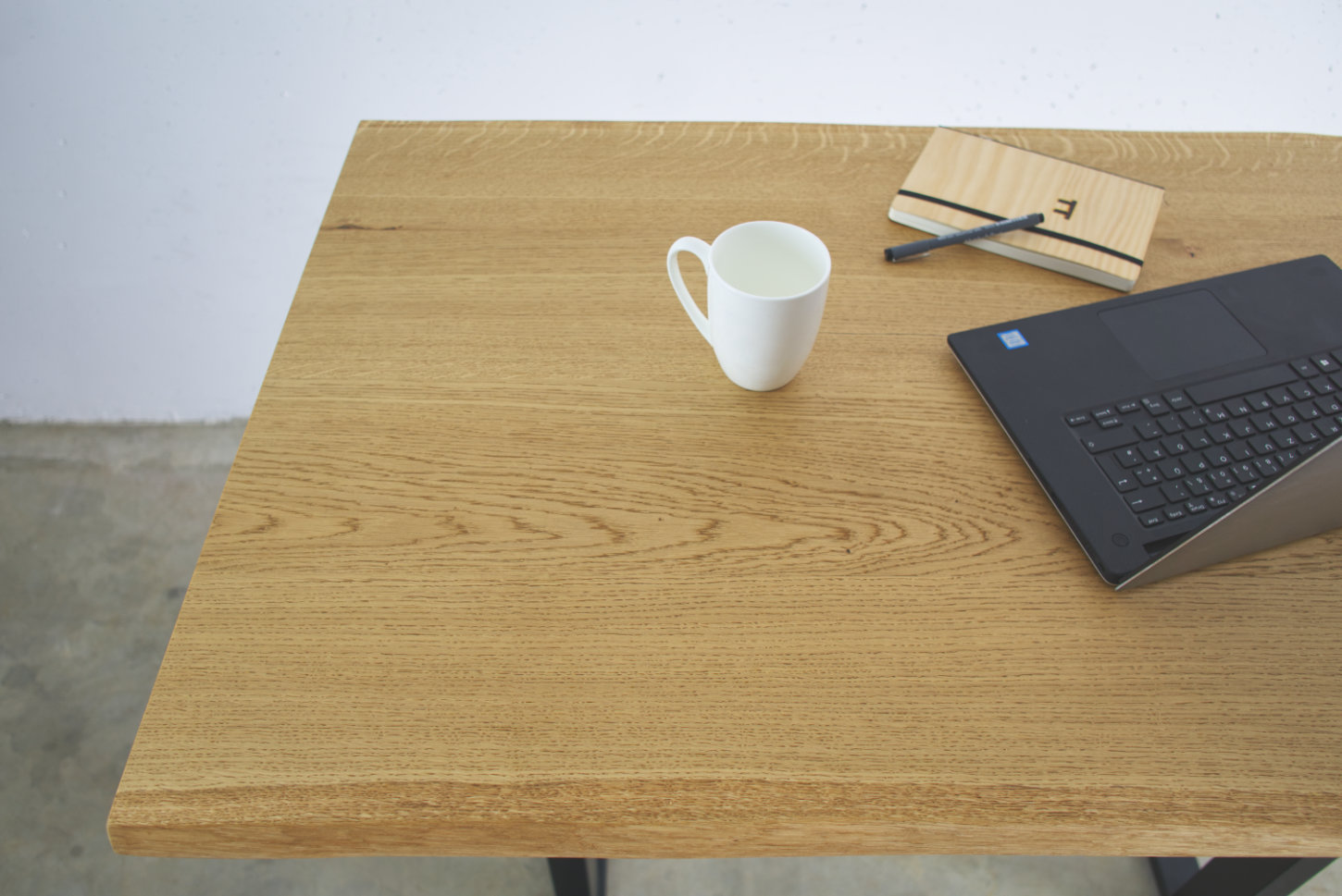 stehtisch eiche massivholz mit baumkante darauf laptop notizbuch und kaffeetasse