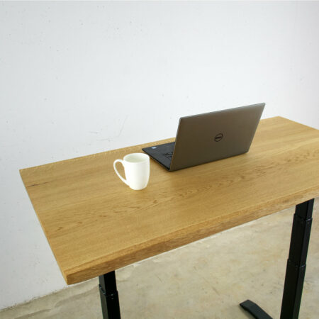 elektrisch höhenverstellbarer tisch aus eiche massivholz mit baumkante darauf ein aufgeklappter laptop und eine weiße kaffeetasse