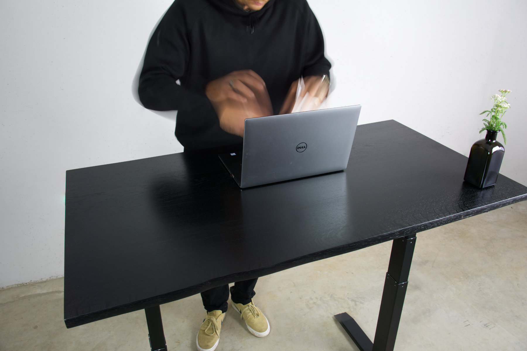 stehtisch in schwarzer eiche massivholz mit baumkante darauf silberner laptop auf dem ein junger mann tippt