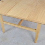 draufsicht auf einen designer massivholztisch mit blick auf ein die holzbeine welche raffinierte rundungen besitzen