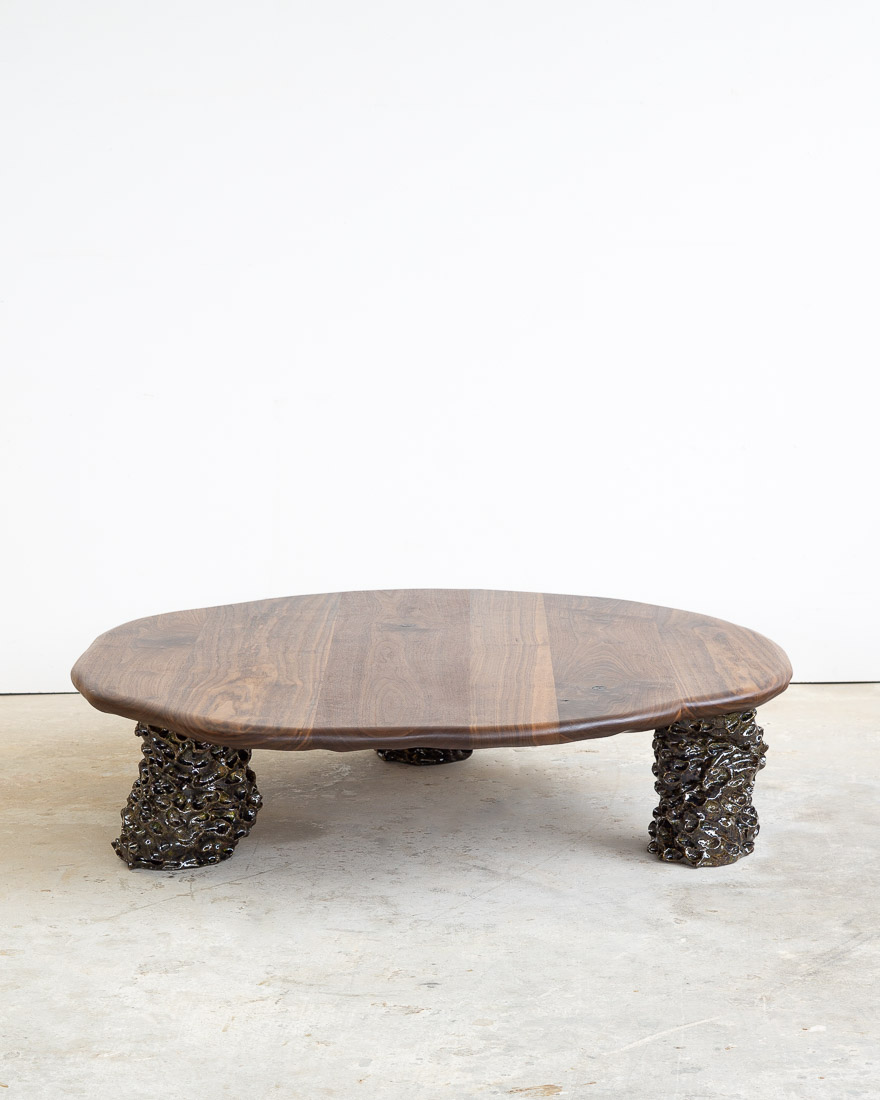 coffee table in walnut with three sculptural legs made of dark green ceramic