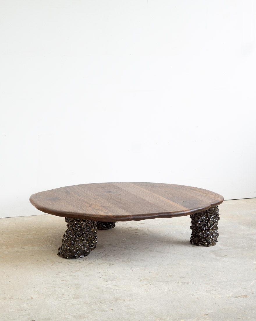 coffee table in walnut with three sculptural legs made of dark green ceramic