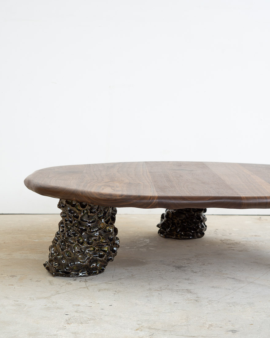 coffee table in walnut with three sculptural legs made of dark green ceramic