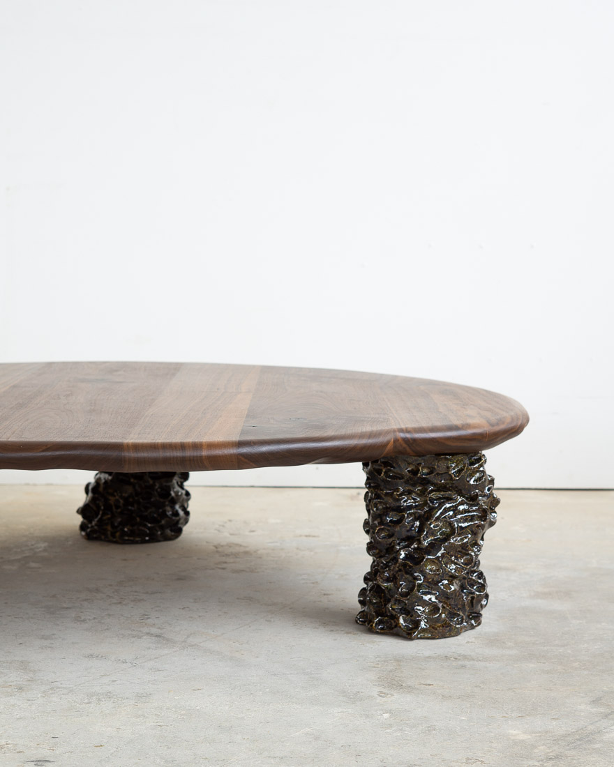 coffee table in walnut with three sculptural legs made of dark green ceramic