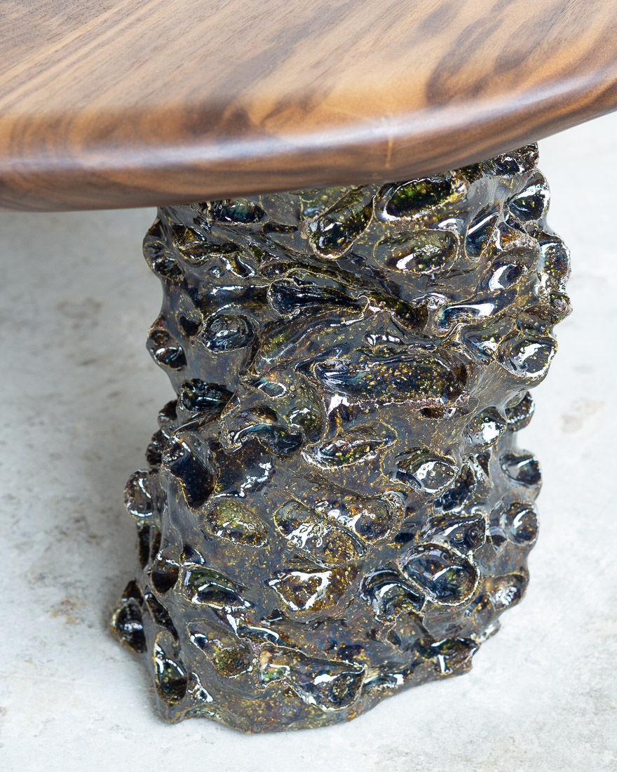coffee table in walnut with three sculptural legs made of dark green ceramic