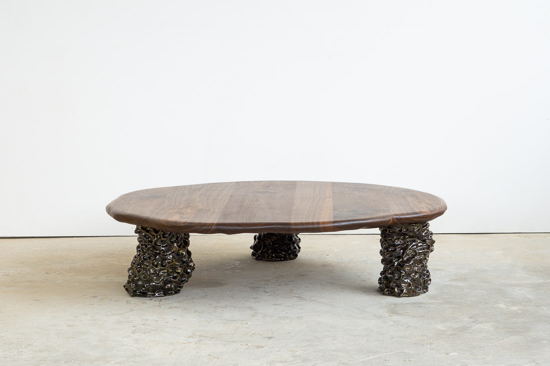 coffee table in walnut with three sculptural legs made of dark green ceramic
