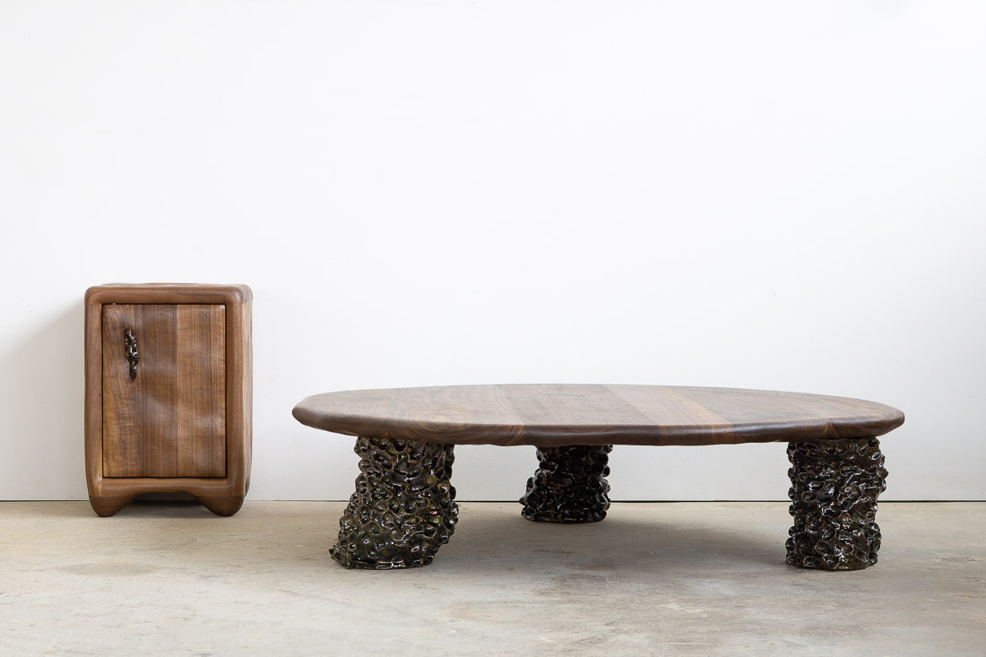 coffee table in walnut with three sculptural legs made of dark green ceramic